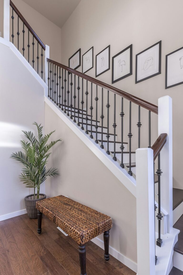 Small entryway landing sequence with a woven bench near a white staircase