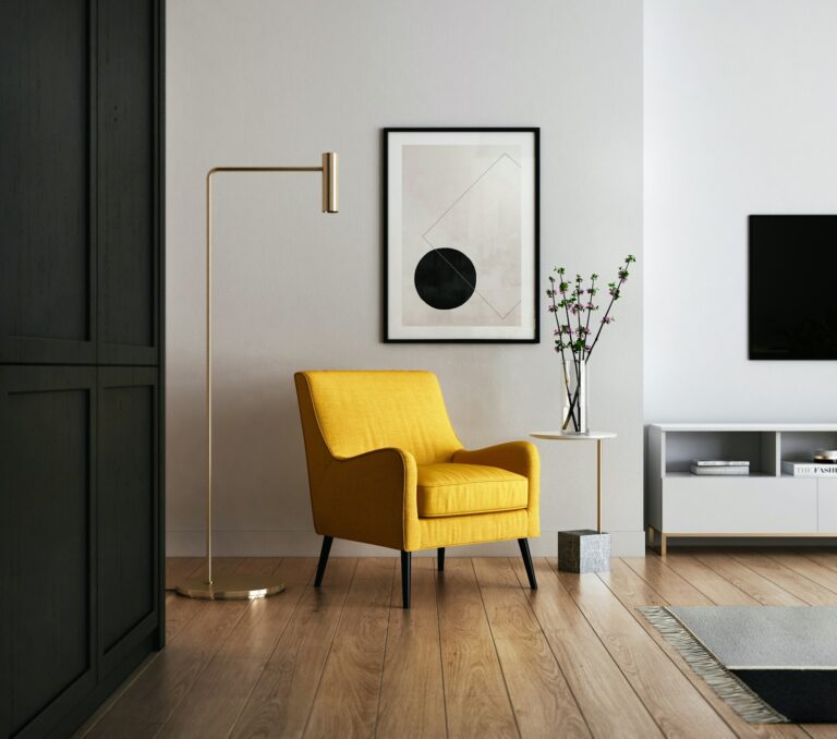Mustard-yellow armchair against a pale wall with a brass floor lamp and framed abstract print